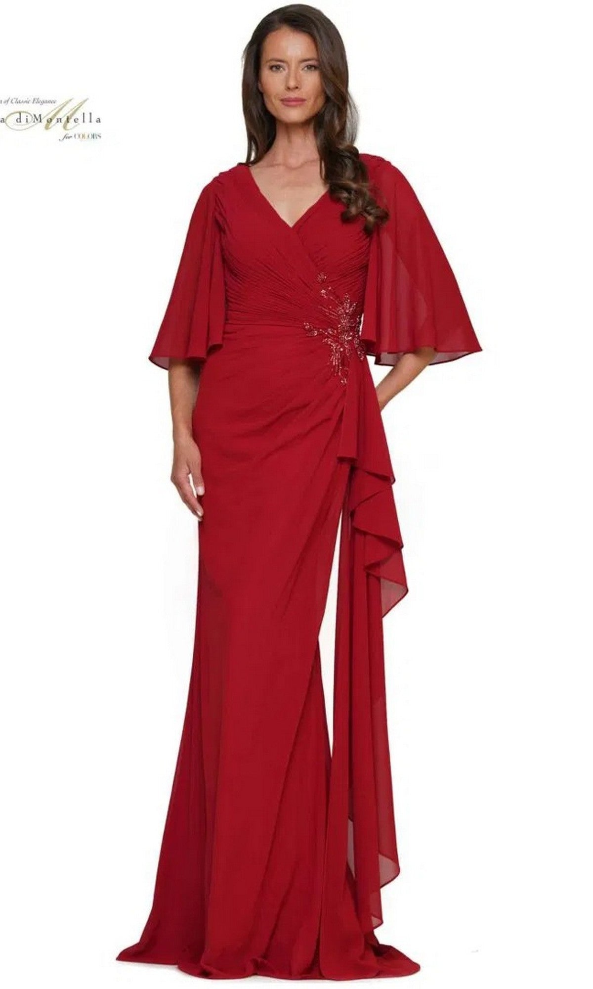 A woman stands facing forward in the Long Formal Dress: Rina Di Montella RD2935, featuring a floor-length wine chiffon design with flutter sleeves, V-neckline, and ruched bodice.